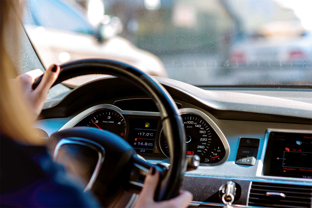 hands of woman driving a car at sunset